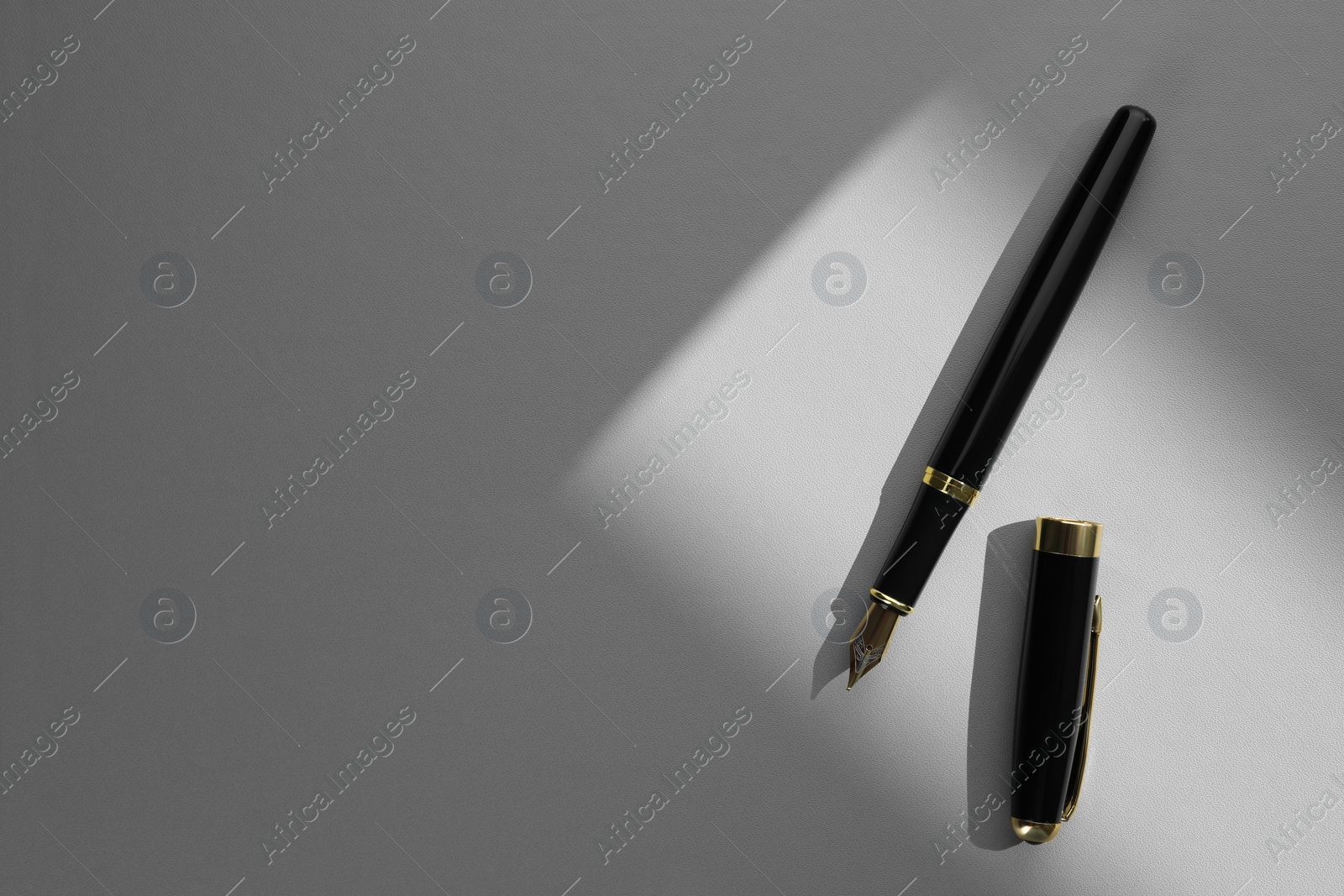 Photo of Stylish fountain pen on light grey textured table, top view. Space for text