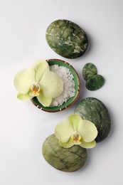 Flat lay composition with spa stones, salt and beautiful flowers on white table