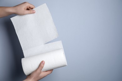 Photo of Woman tearing paper towels on grey background, closeup. Space for text