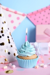 Delicious birthday cupcake with burning candle, marshmallows and party decor on color background