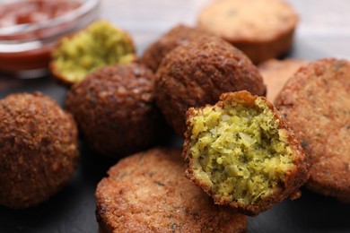 Photo of Delicious vegan cutlets and falafel balls on slate board, closeup