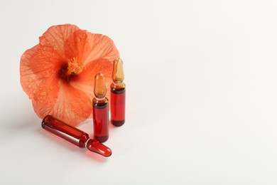 Skincare ampoules and hibiscus flower on white background. Space for text