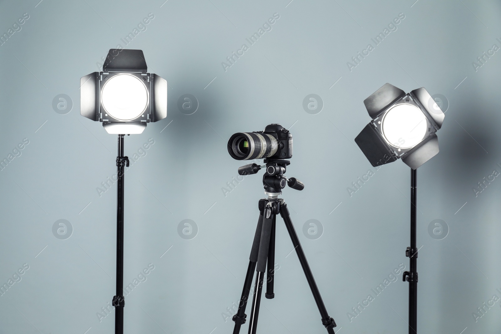 Photo of Professional video camera and lighting equipment on grey background