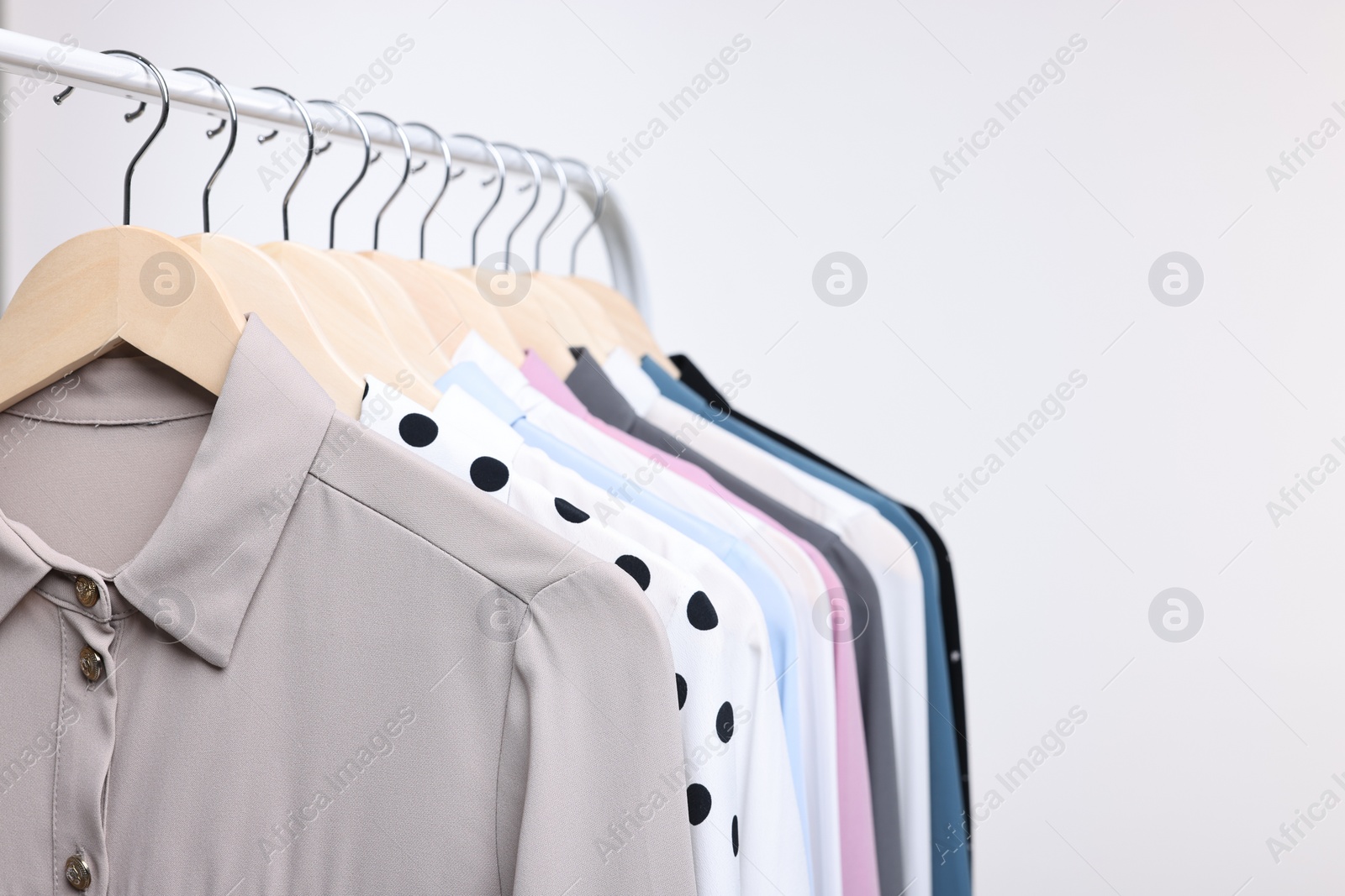 Photo of Dry-cleaning service. Many different clothes hanging on rack against white background, space for text
