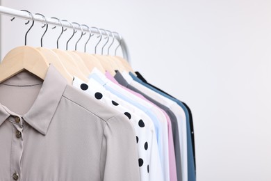 Dry-cleaning service. Many different clothes hanging on rack against white background, space for text