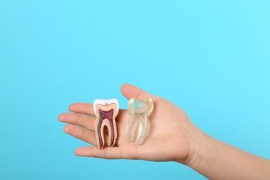 Photo of Woman holding educational model of tooth in hand on color background. Space for text