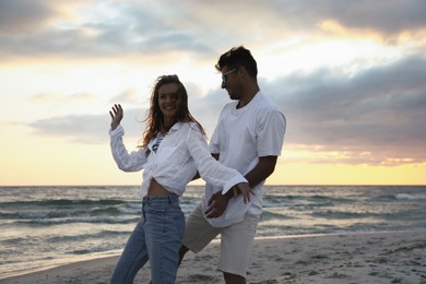 Happy couple dancing on beach at sunset