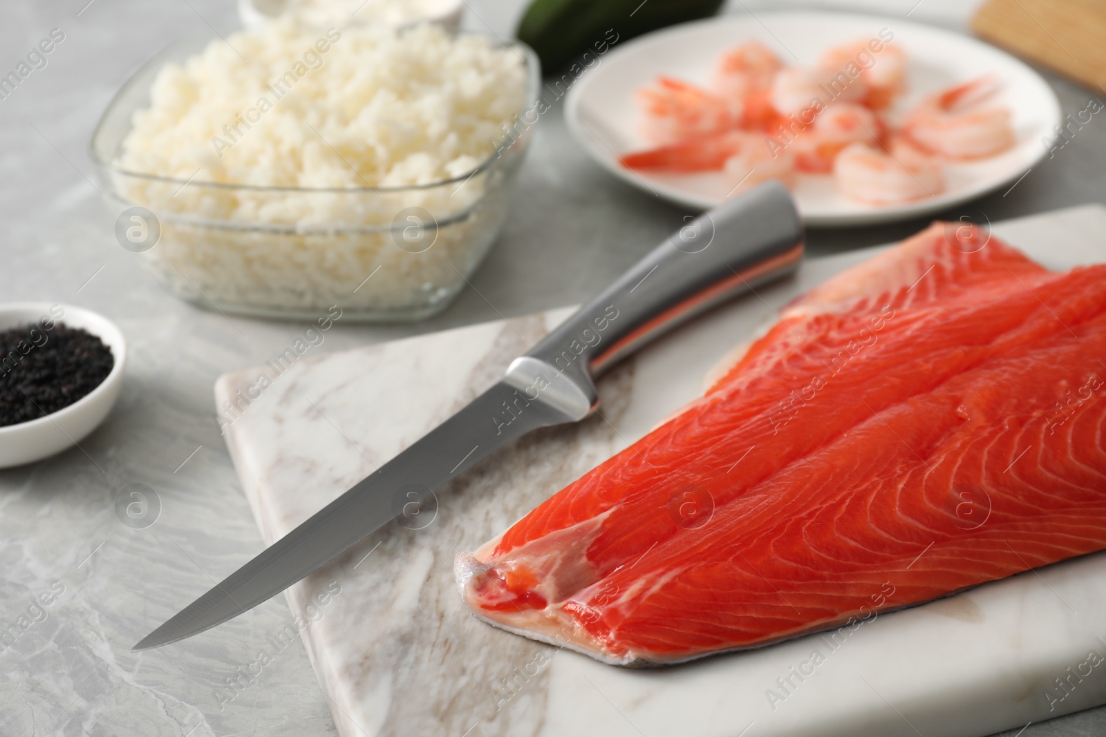 Photo of Fresh salmon and other ingredients for sushi on grey marble table, closeup