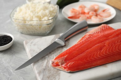 Fresh salmon and other ingredients for sushi on grey marble table, closeup