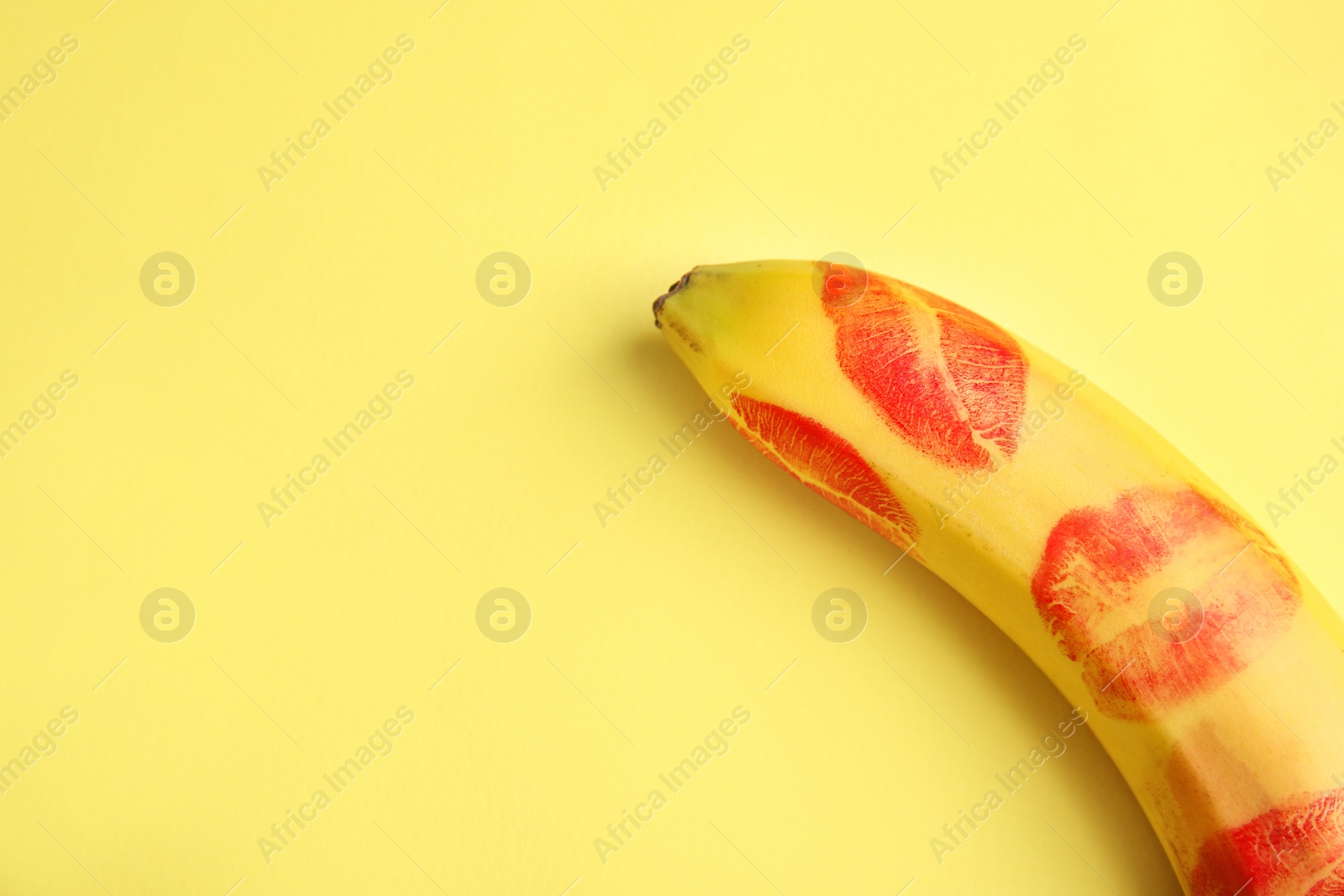 Photo of Fresh banana with red lipstick marks on yellow background, space for text. Oral sex concept