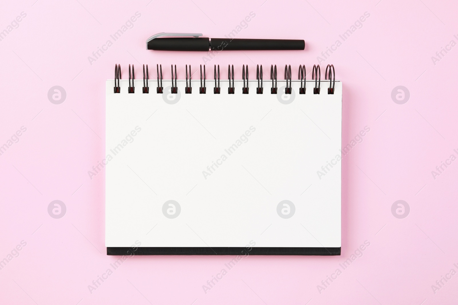 Photo of Notebook and pen on pale pink background, flat lay