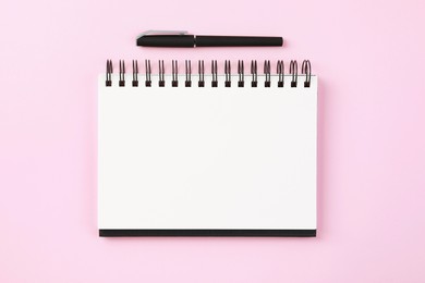 Photo of Notebook and pen on pale pink background, flat lay