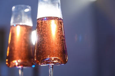 Photo of Glasses of rose champagne on color background, closeup. Space for text