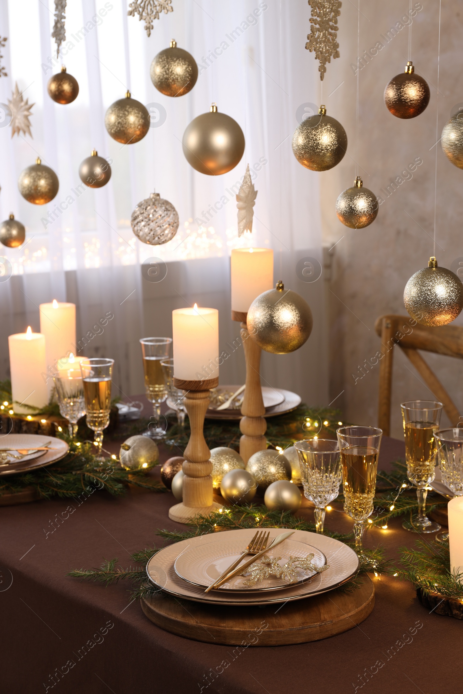 Photo of Christmas table setting with burning candles and festive decor