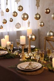 Christmas table setting with burning candles and festive decor