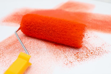 Roller brush and strokes of orange paint on white background, closeup