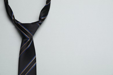 Photo of Striped necktie on light background, top view. Space for text