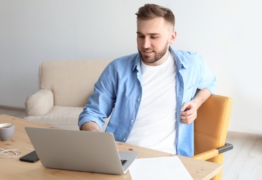 Photo of Young man working with laptop at desk. Home office