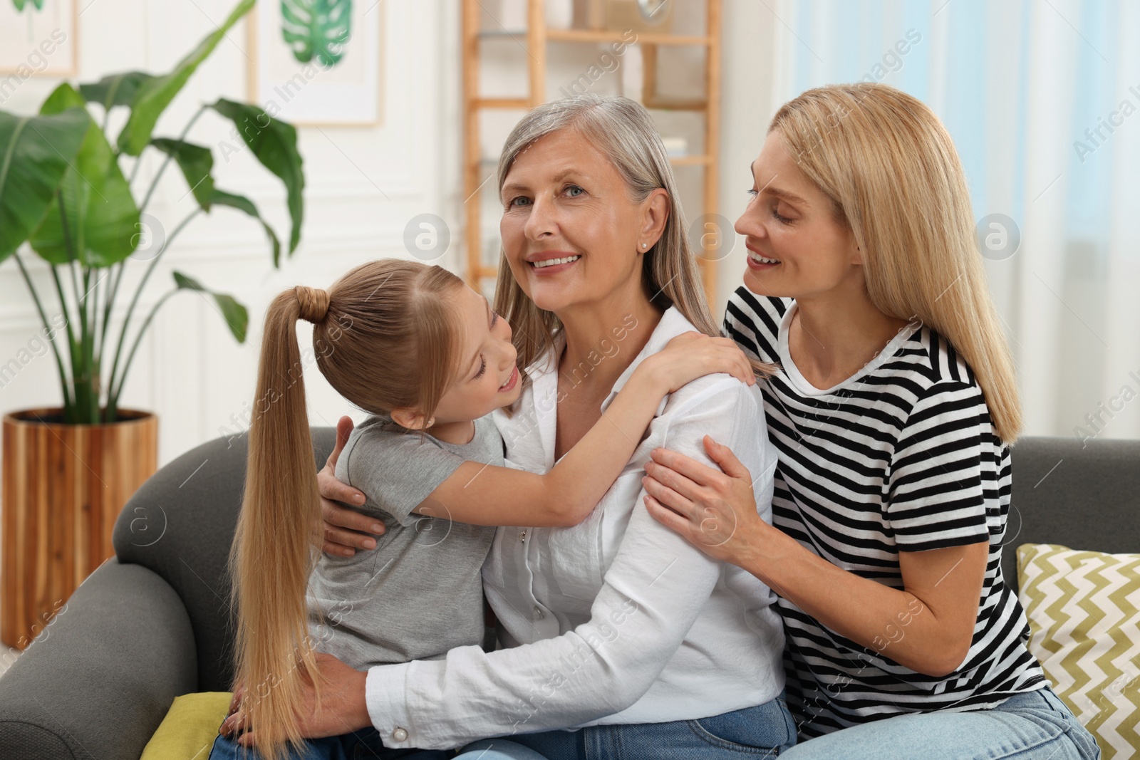 Photo of Three generations. Happy grandmother, her daughter and granddaughter at home