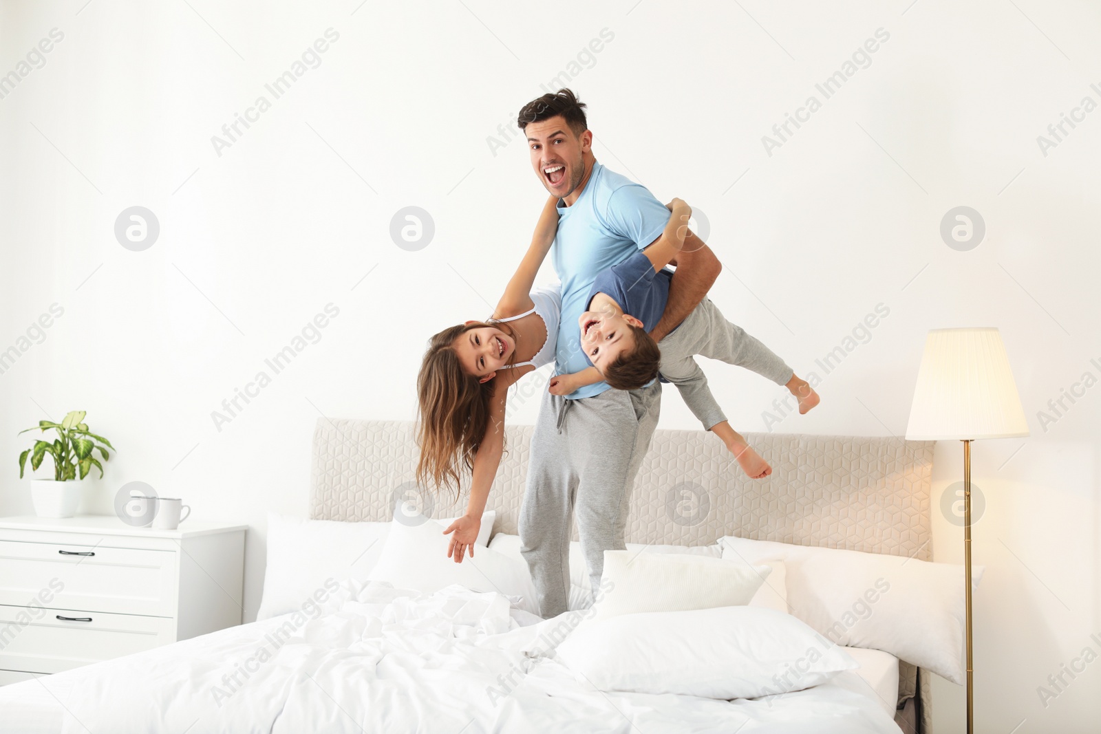 Photo of Happy father playing with his children in bedroom