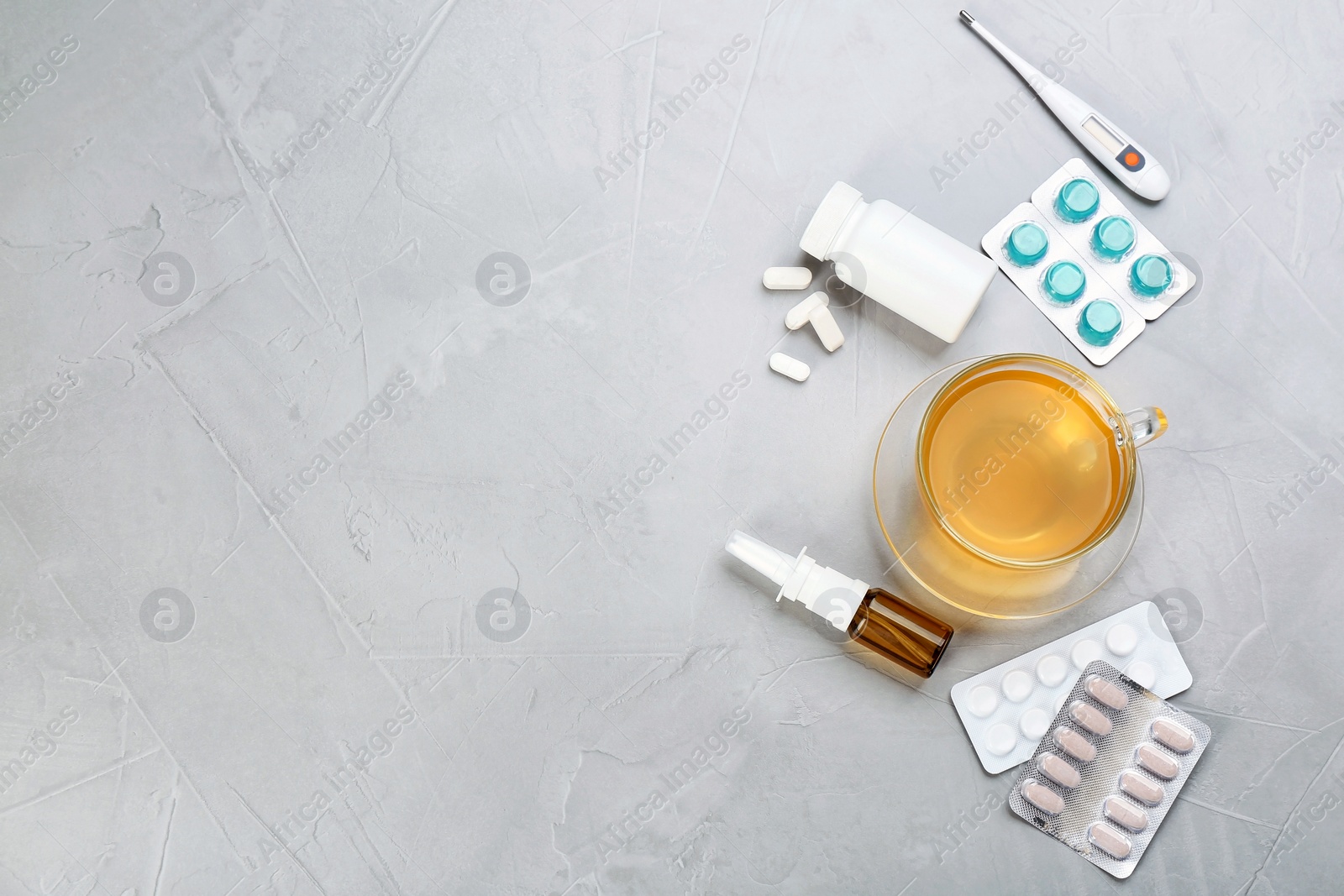 Photo of Cup with hot tea, pills and drugs for cold on table, top view