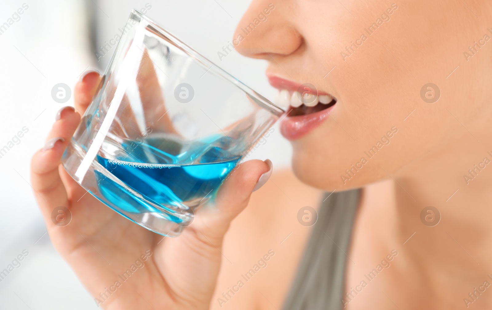 Photo of Woman rinsing mouth with mouthwash in bathroom, closeup.Teeth care