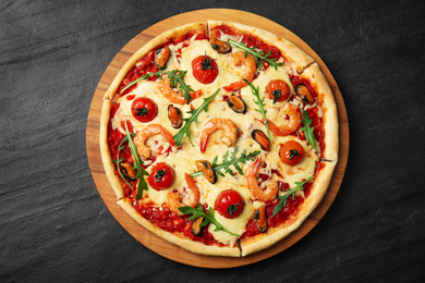 Photo of Delicious seafood pizza on black table, top view