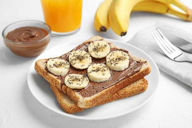 Photo of Slice of bread with chocolate paste and banana on white table