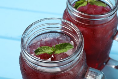 Photo of Delicious iced hibiscus tea with mint on light blue table, closeup