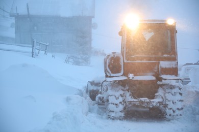 Tractor cleaning road in snowstorm. Winter season