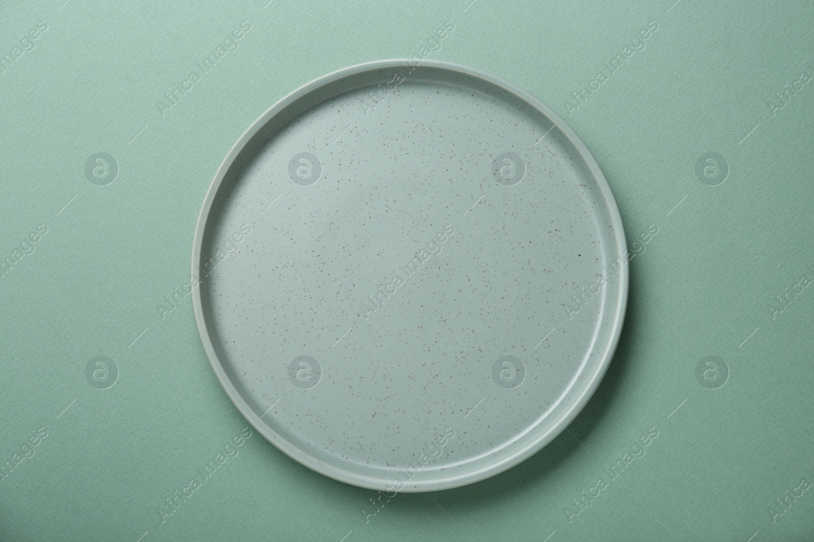 Photo of Empty ceramic plate on green background, top view