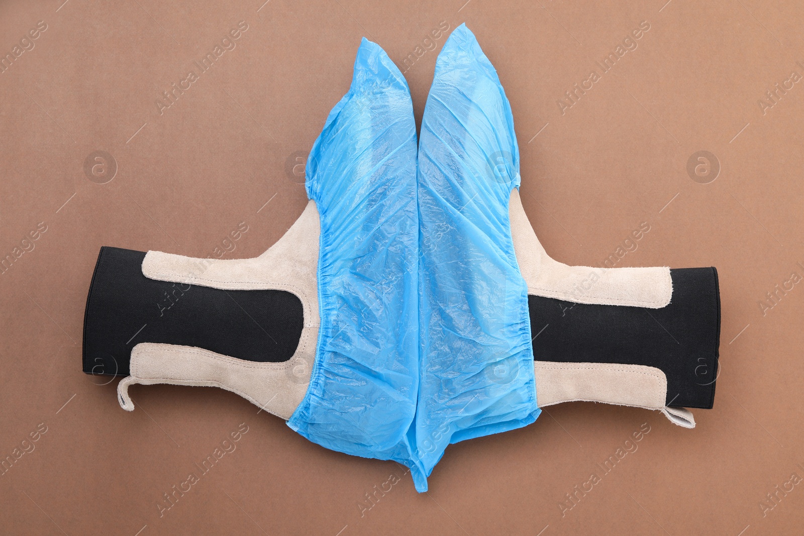 Photo of Women's boots in shoe covers on brown background, top view