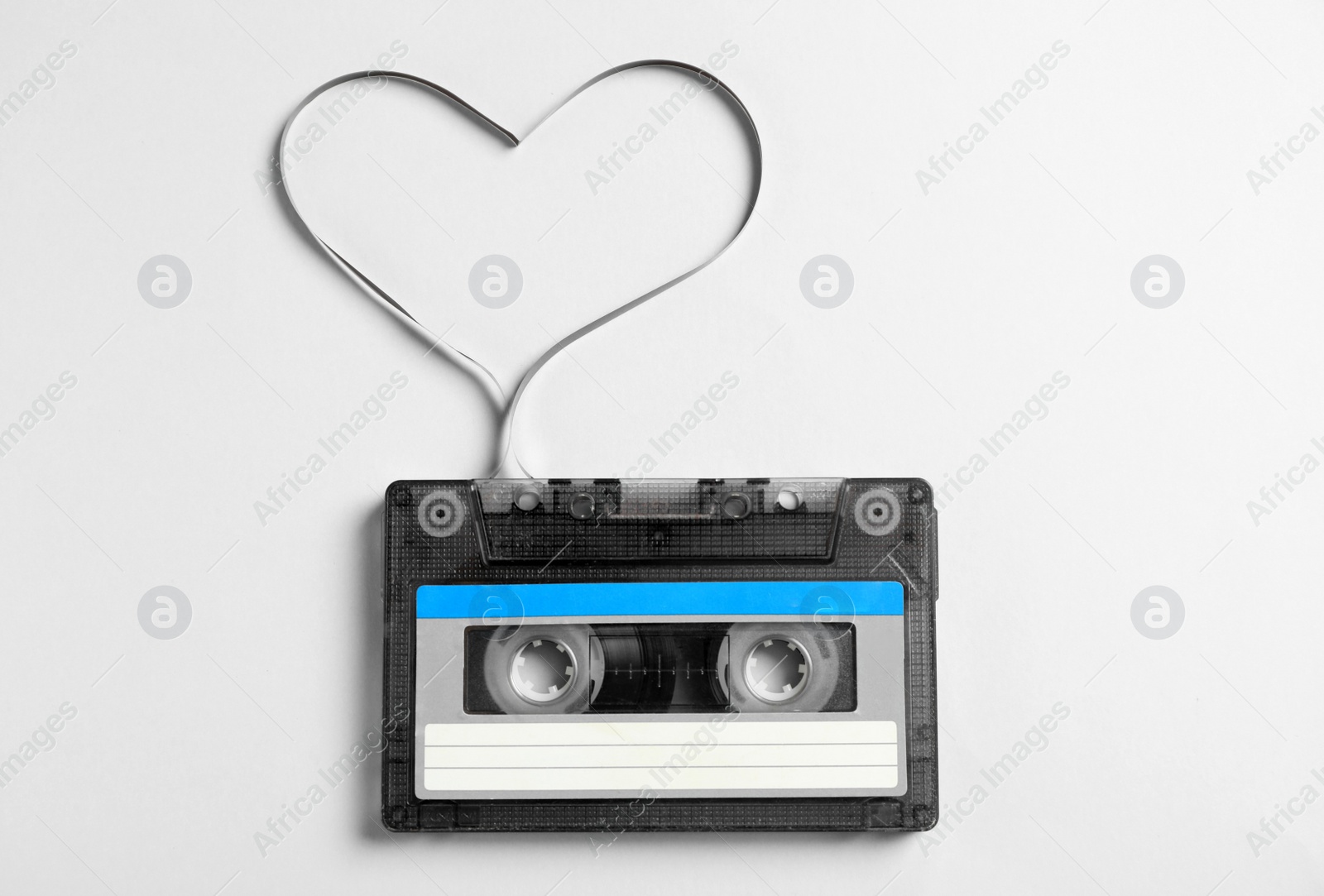 Photo of Music cassette and heart made with tape on white background, top view. Listening love song