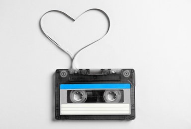 Photo of Music cassette and heart made with tape on white background, top view. Listening love song