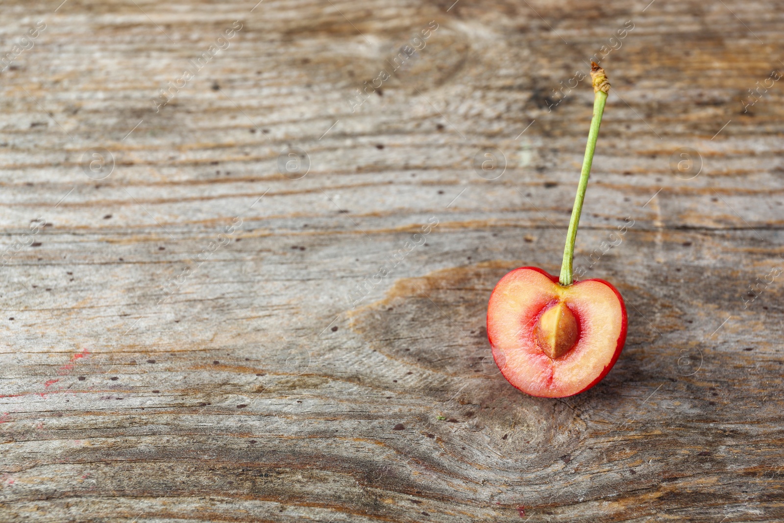 Photo of Half of ripe red cherry on wooden background