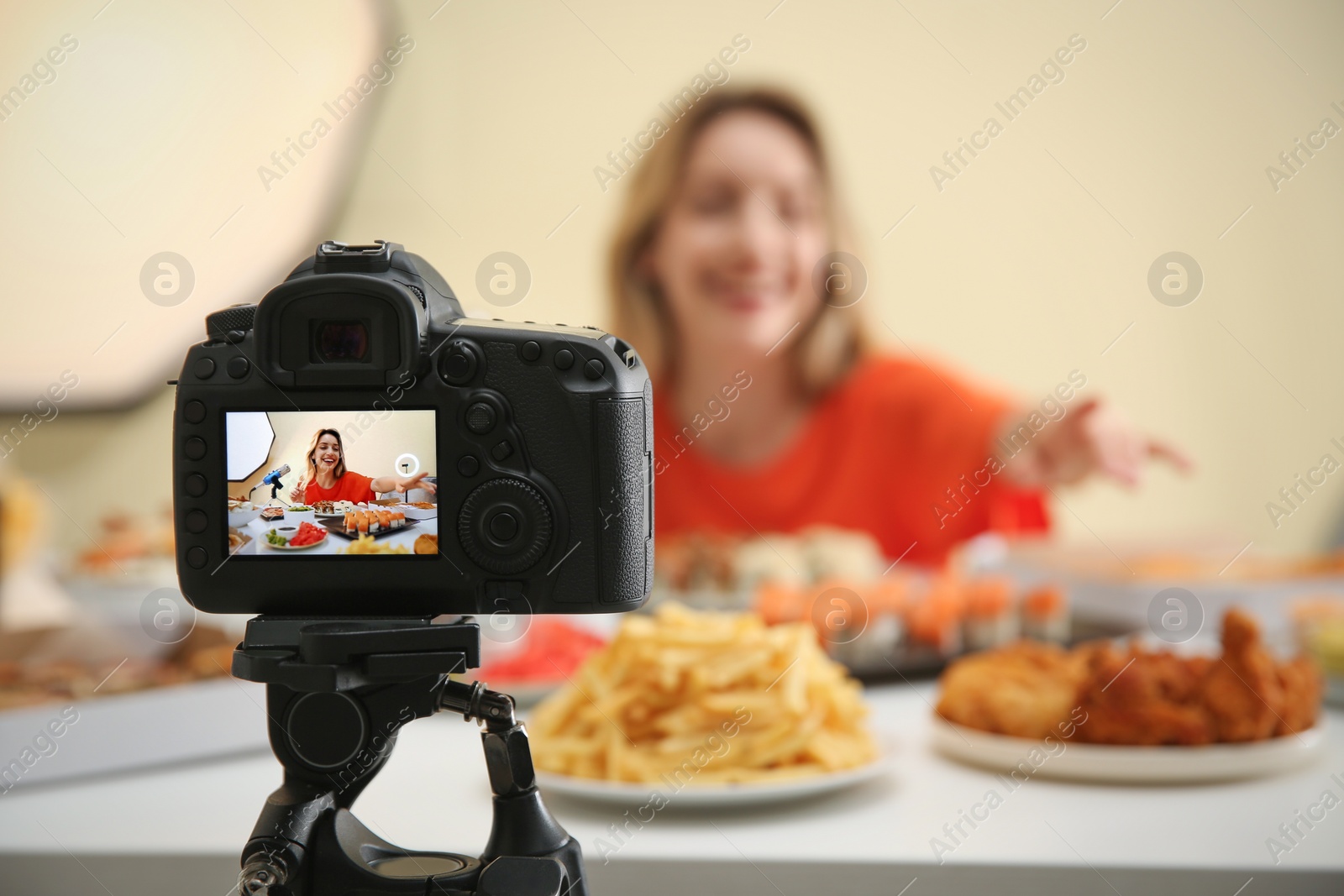 Photo of Food blogger recording eating show against light background, focus on camera screen. Mukbang vlog