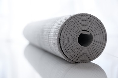 Photo of Rolled karemat or fitness mat on tiled floor, closeup