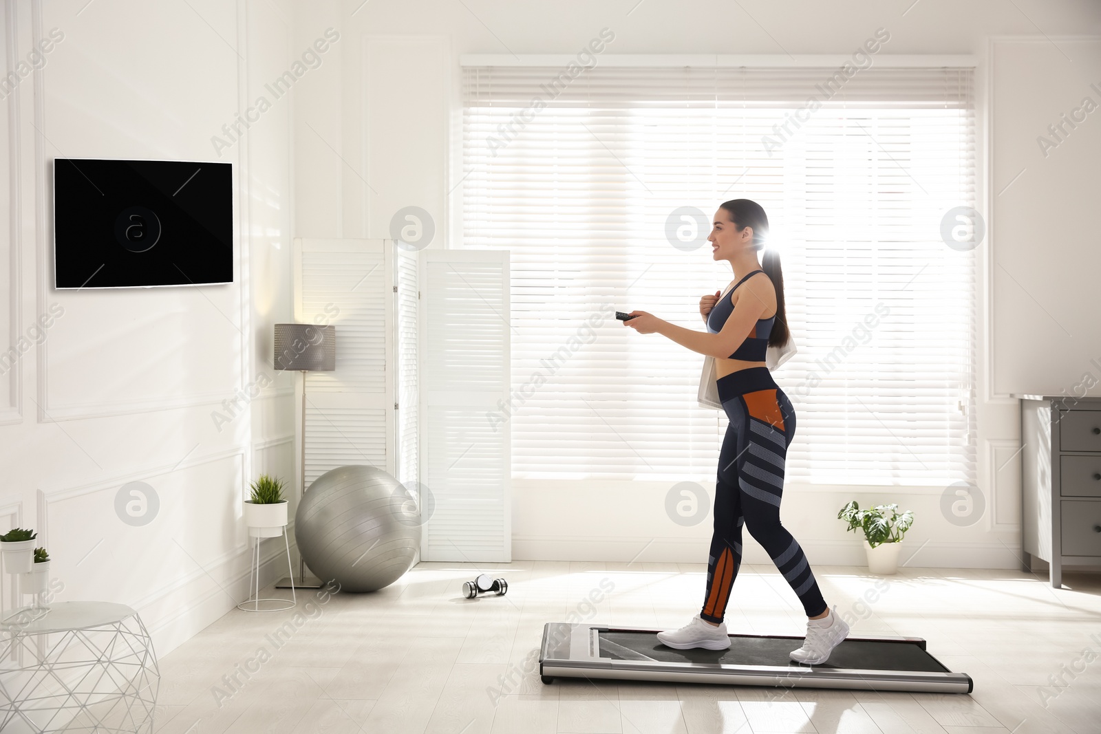 Photo of Sporty woman training on walking treadmill at home