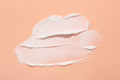 Photo of Sample of face cream on coral background, top view