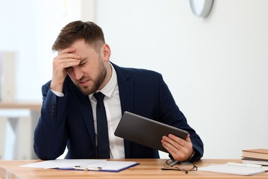 Photo of Man suffering from migraine at workplace in office