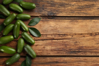 Photo of Fresh avocados with green leaves on wooden table, flat lay. Space for text