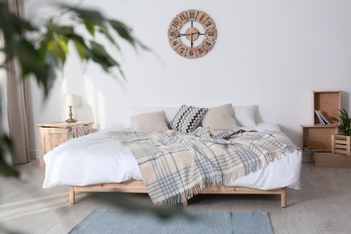 Bed with pillows and plaid in modern room interior