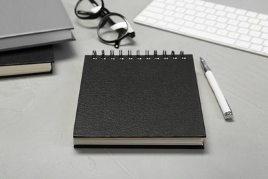 Black notebook and pen on light grey table