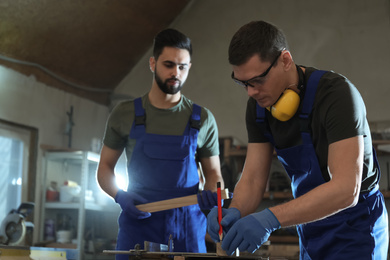 Professional carpenters working with wood in shop