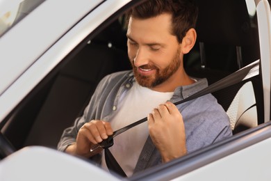 Photo of Smiling man pulling seat belt in car
