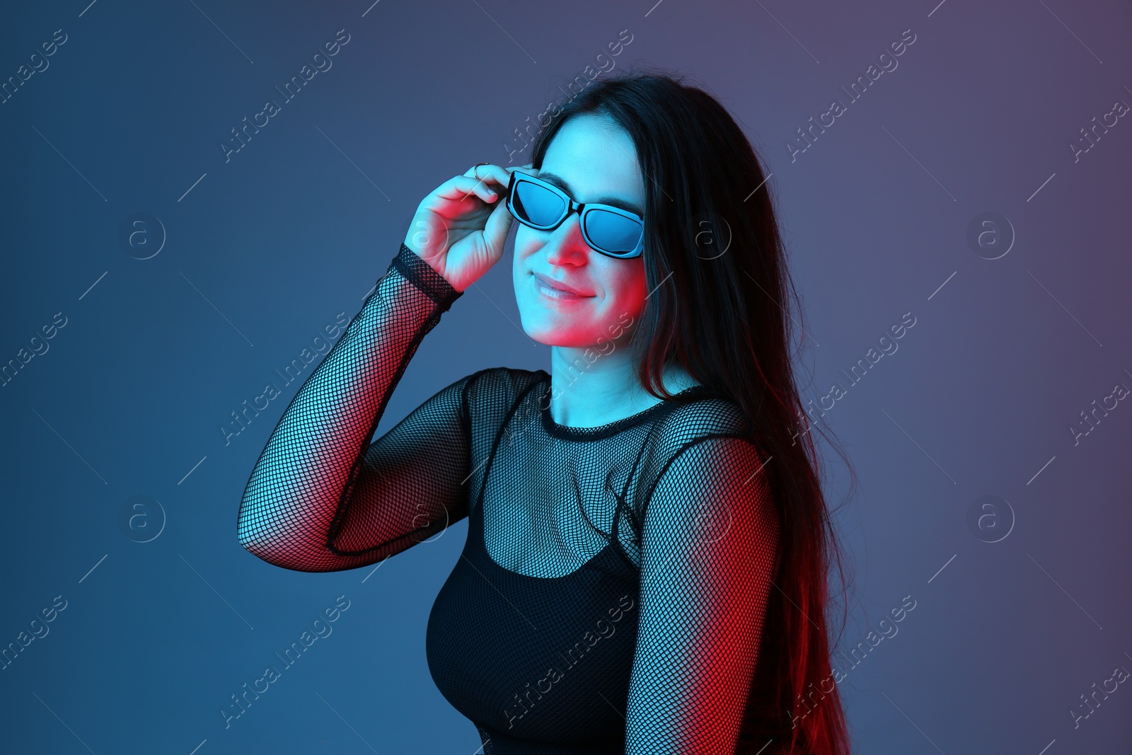 Photo of Portrait of beautiful young woman with sunglasses on color background