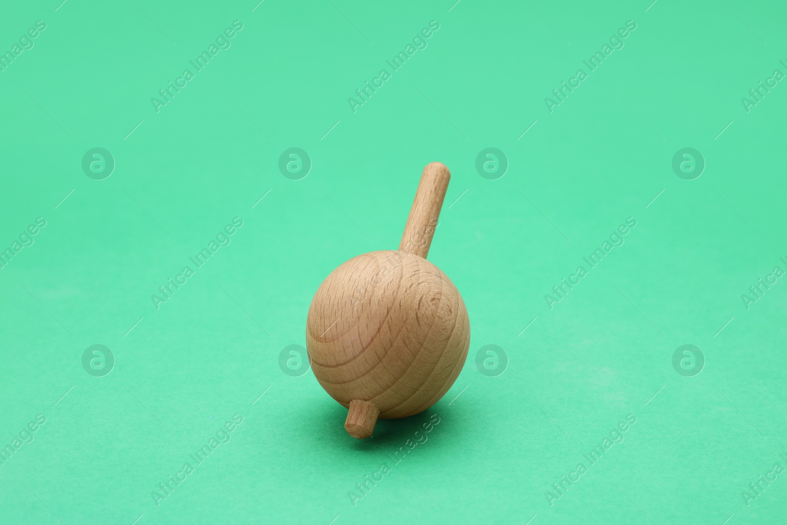 Photo of One wooden spinning top on green background. Toy whirligig