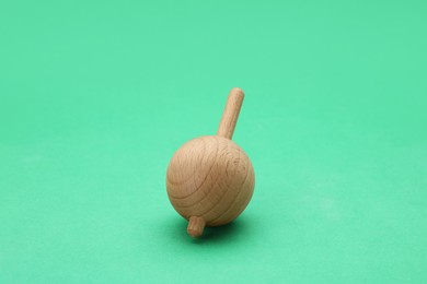 Photo of One wooden spinning top on green background. Toy whirligig
