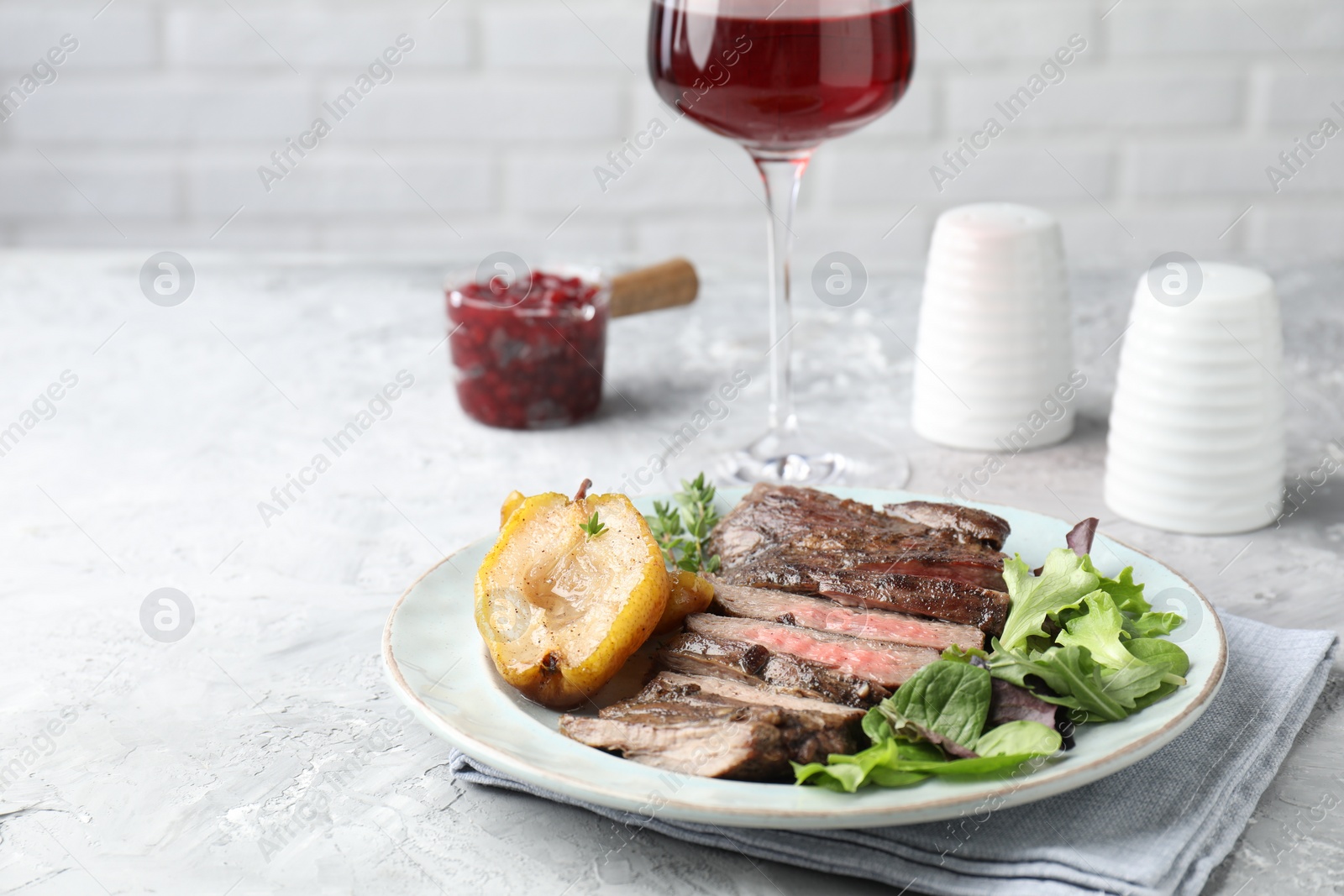 Photo of Delicious roasted beef meat, caramelized pear and greens served on light table. Space for text