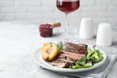 Delicious roasted beef meat, caramelized pear and greens served on light table. Space for text